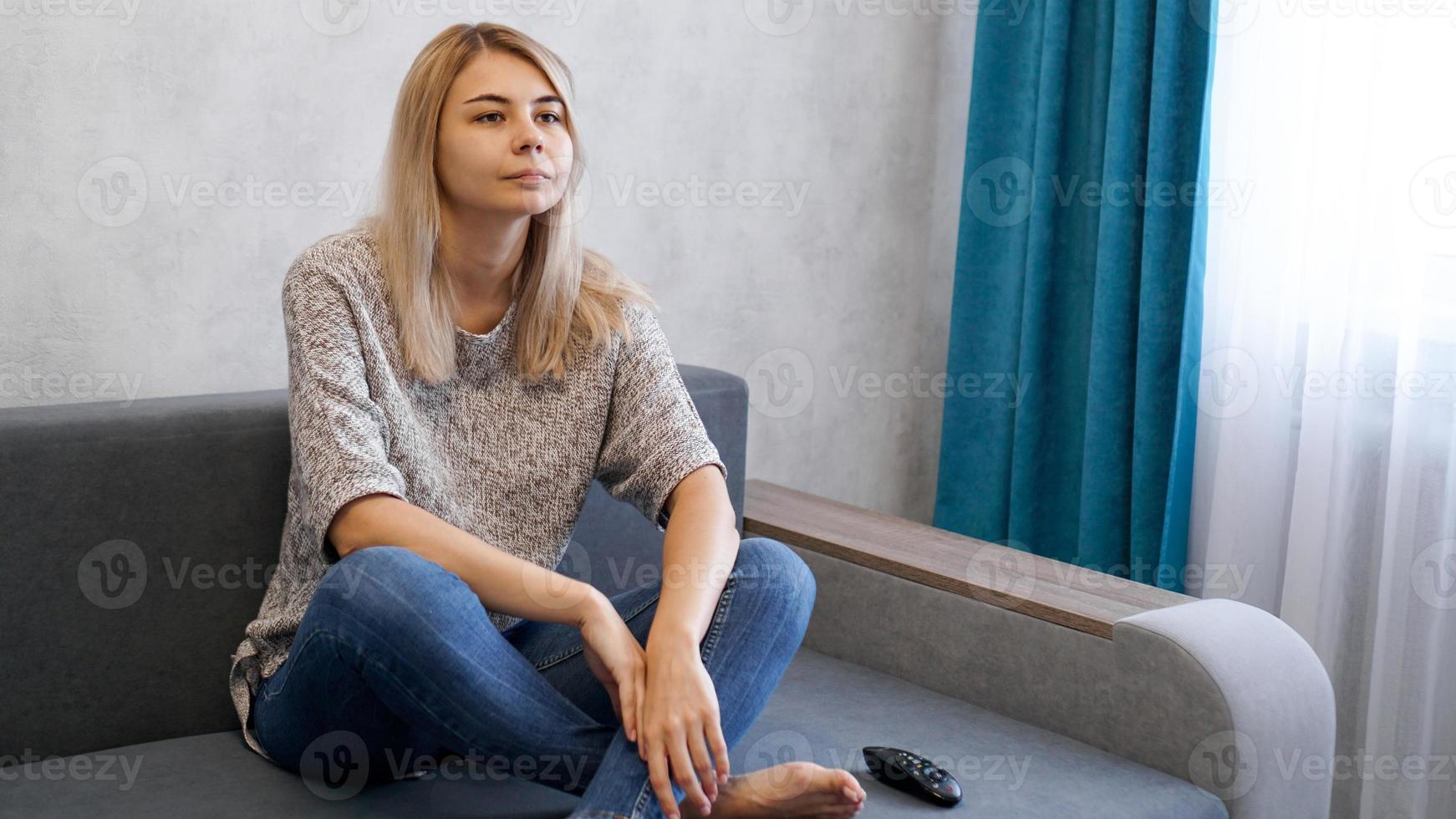 una giovane donna attraente che guarda la tv sul divano foto