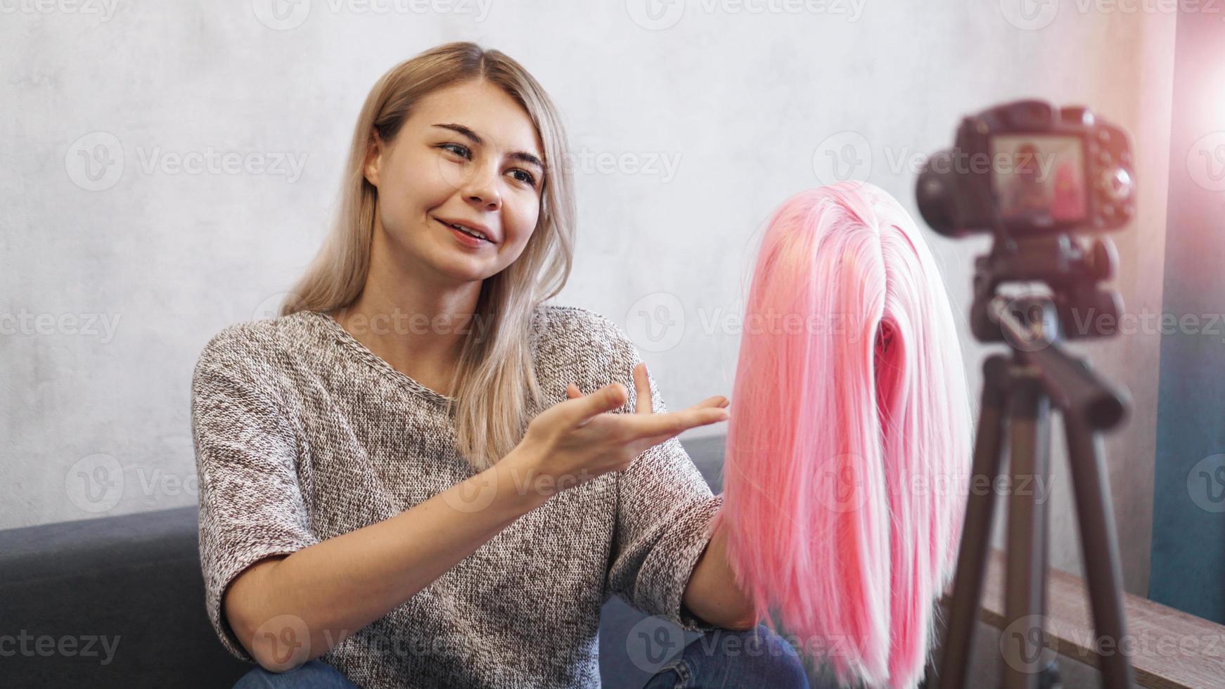 blogger donna registra video. lei mostra la parrucca rosa foto