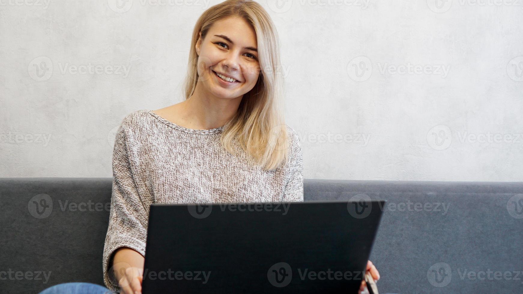 casual giovane donna che utilizza laptop in soggiorno foto