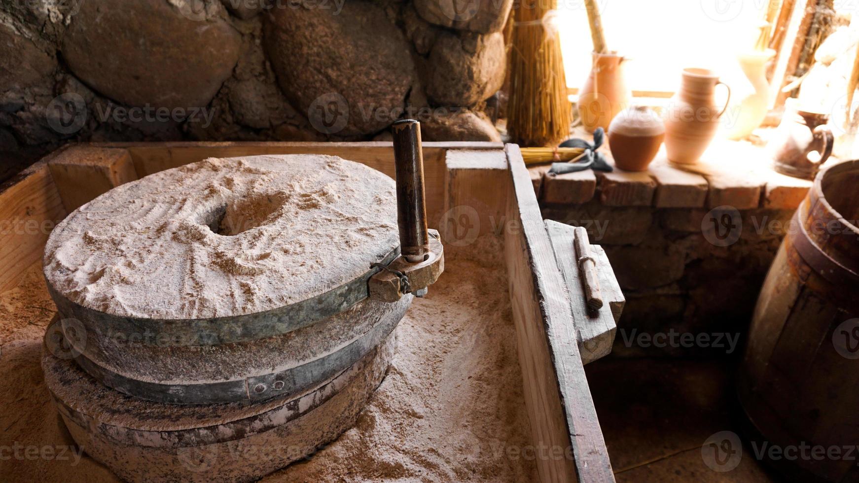 un antico mulino a mano in pietra e legno. dispositivo di macinazione della farina foto