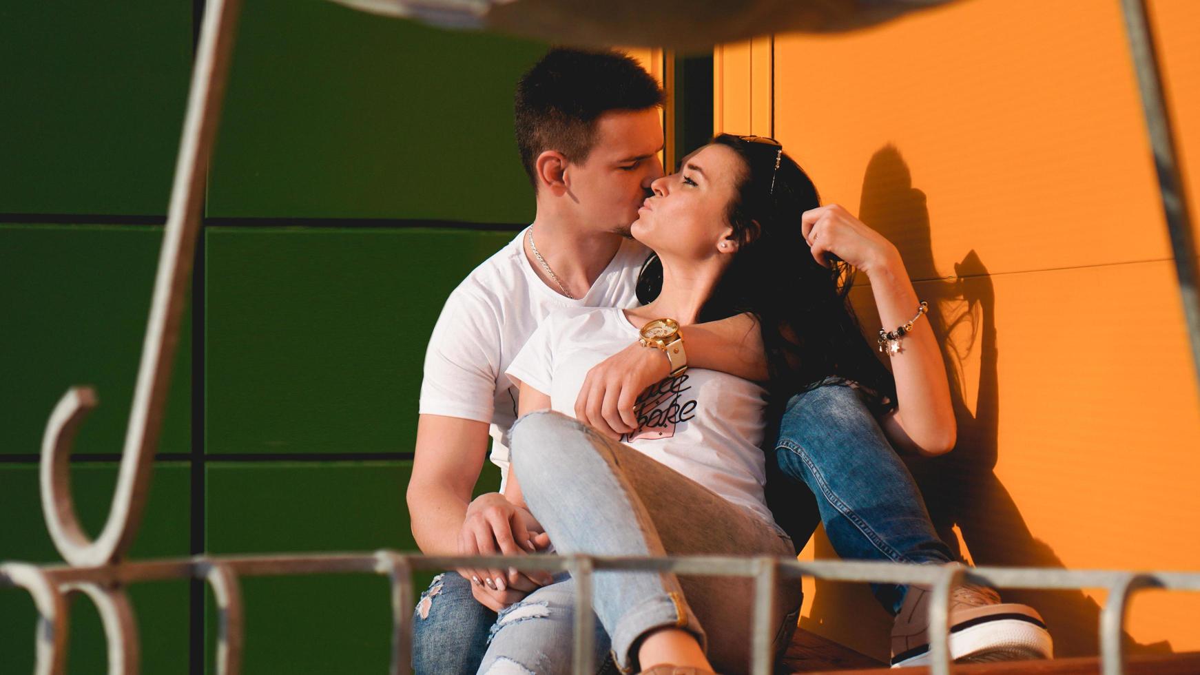 coppia che si bacia contro il muro giallo e verde isolato in città foto
