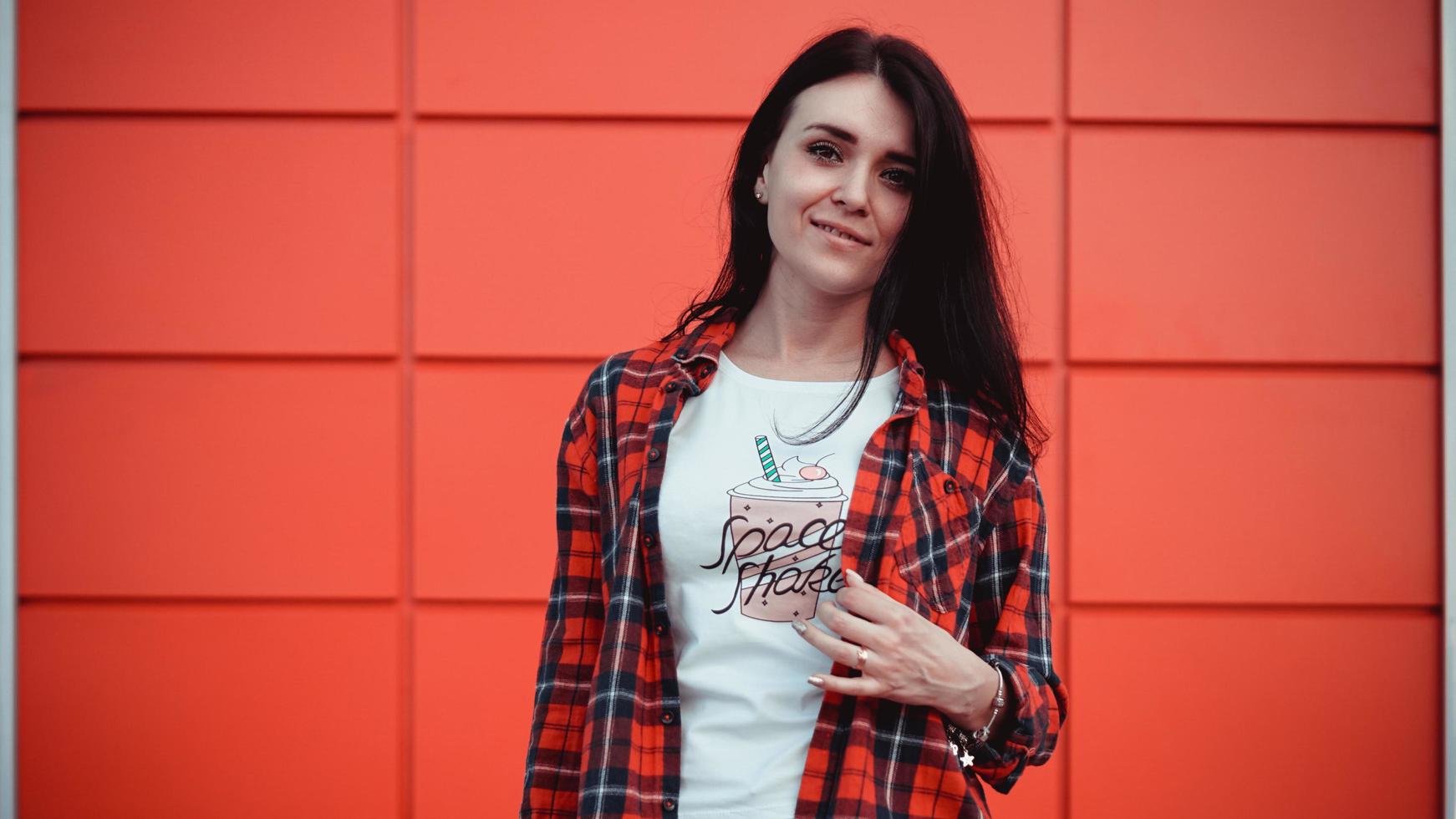 ritratto di una bellissima giovane donna con una camicia a quadri rossa su un muro rosso foto