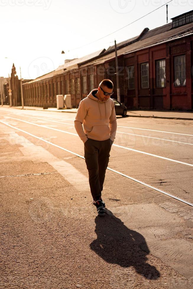 hipster che cammina per strada con un muro di mattoni rossi foto