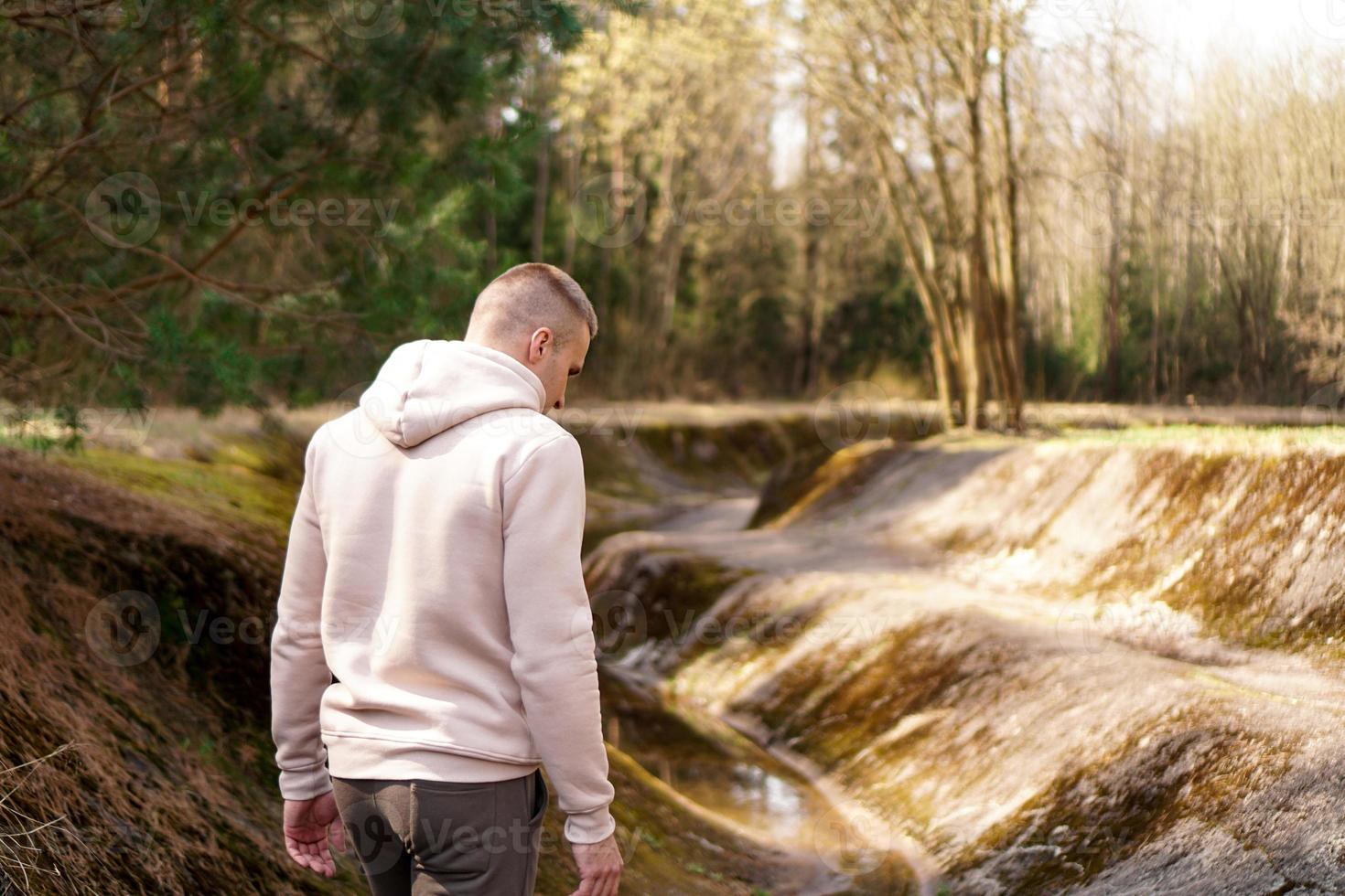 un uomo cammina nei boschi vicino a un canale a remi o a un fiume di montagna foto