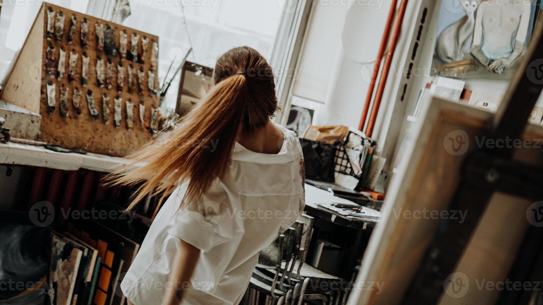 bella pittrice che balla mentre dipinge in un laboratorio d'arte foto