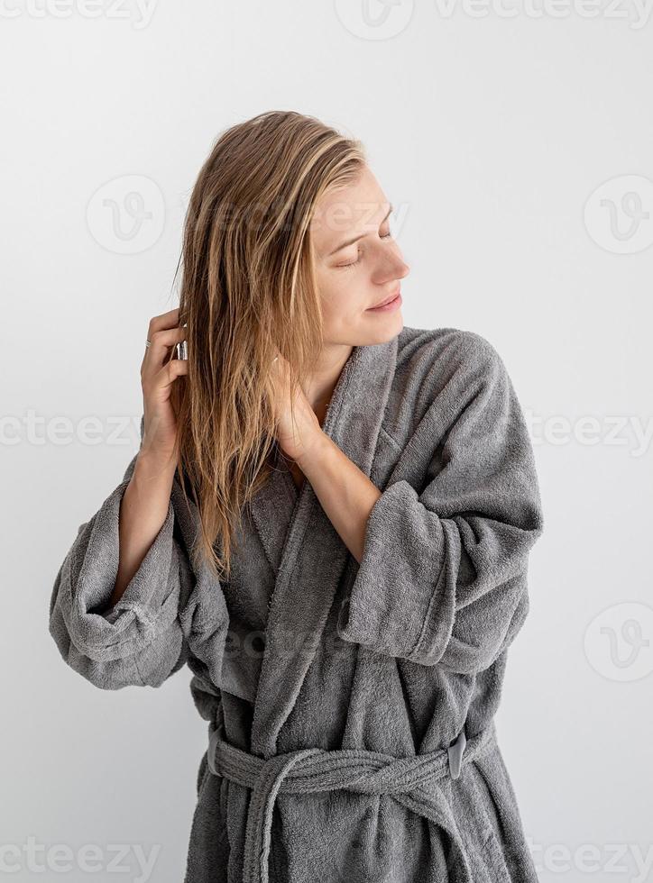 giovane donna felice che applica la maschera per capelli in bagno foto