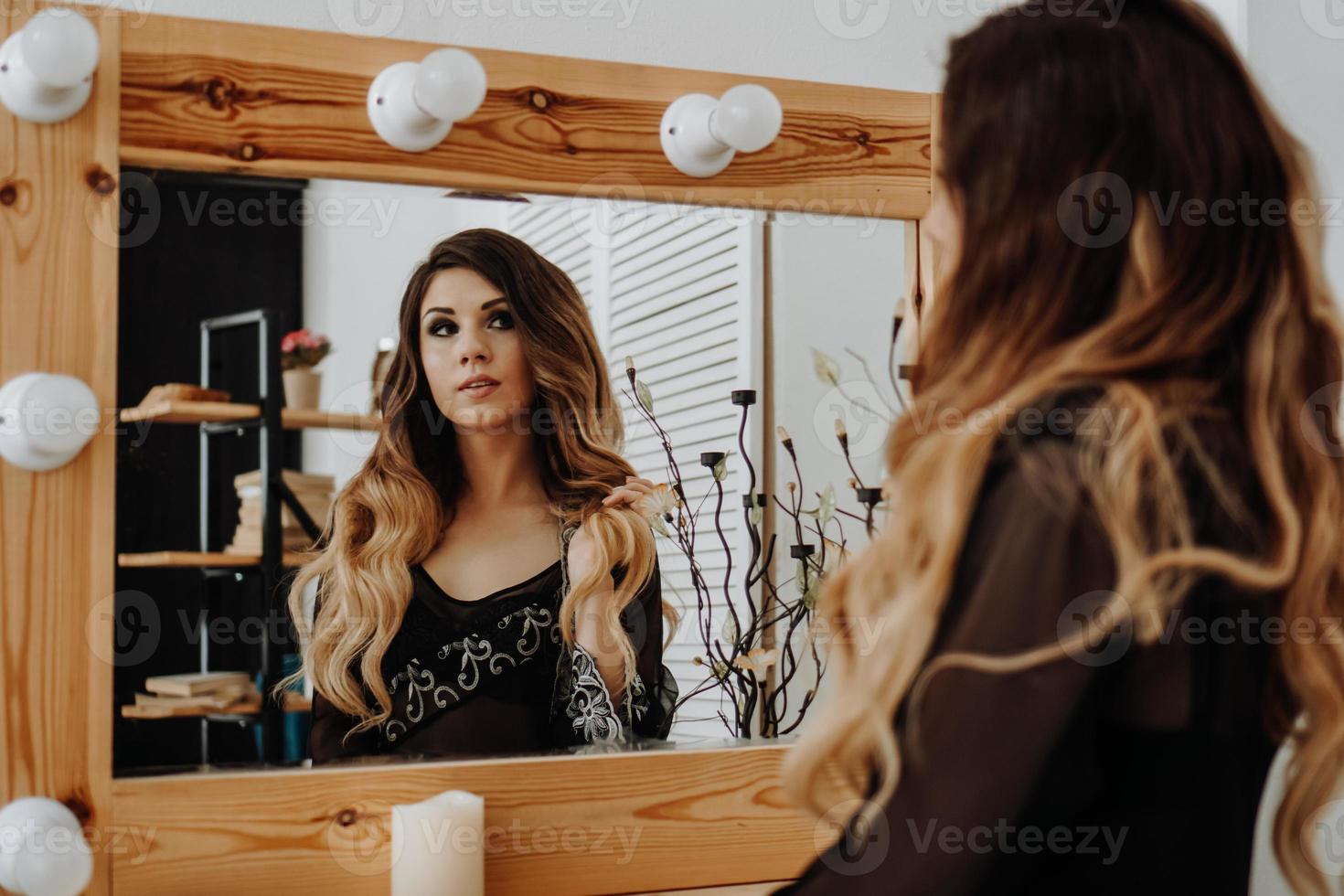 bella giovane donna che guarda il suo riflesso in uno specchietto foto