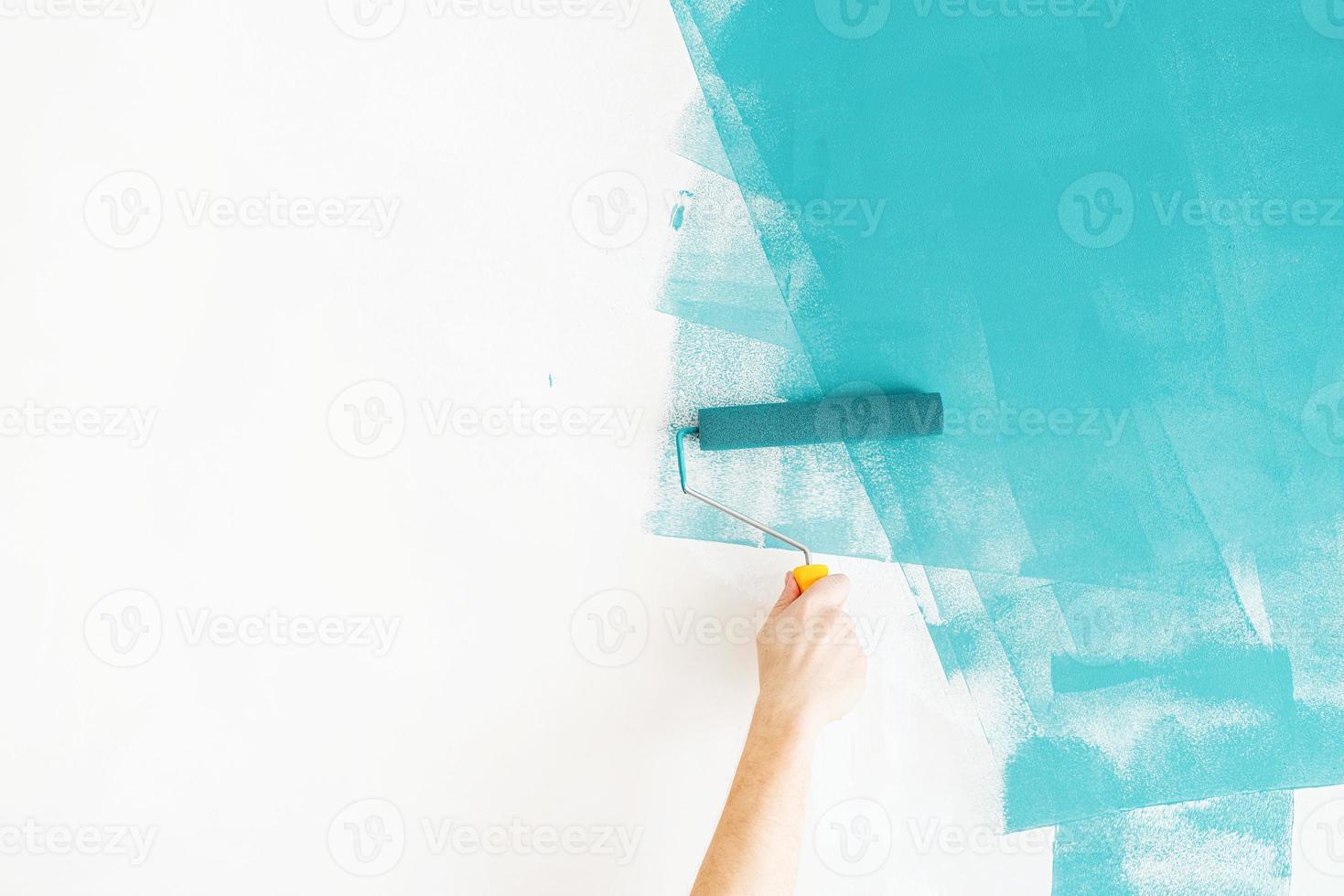 uomo che colora la parete di blu con un rullo foto