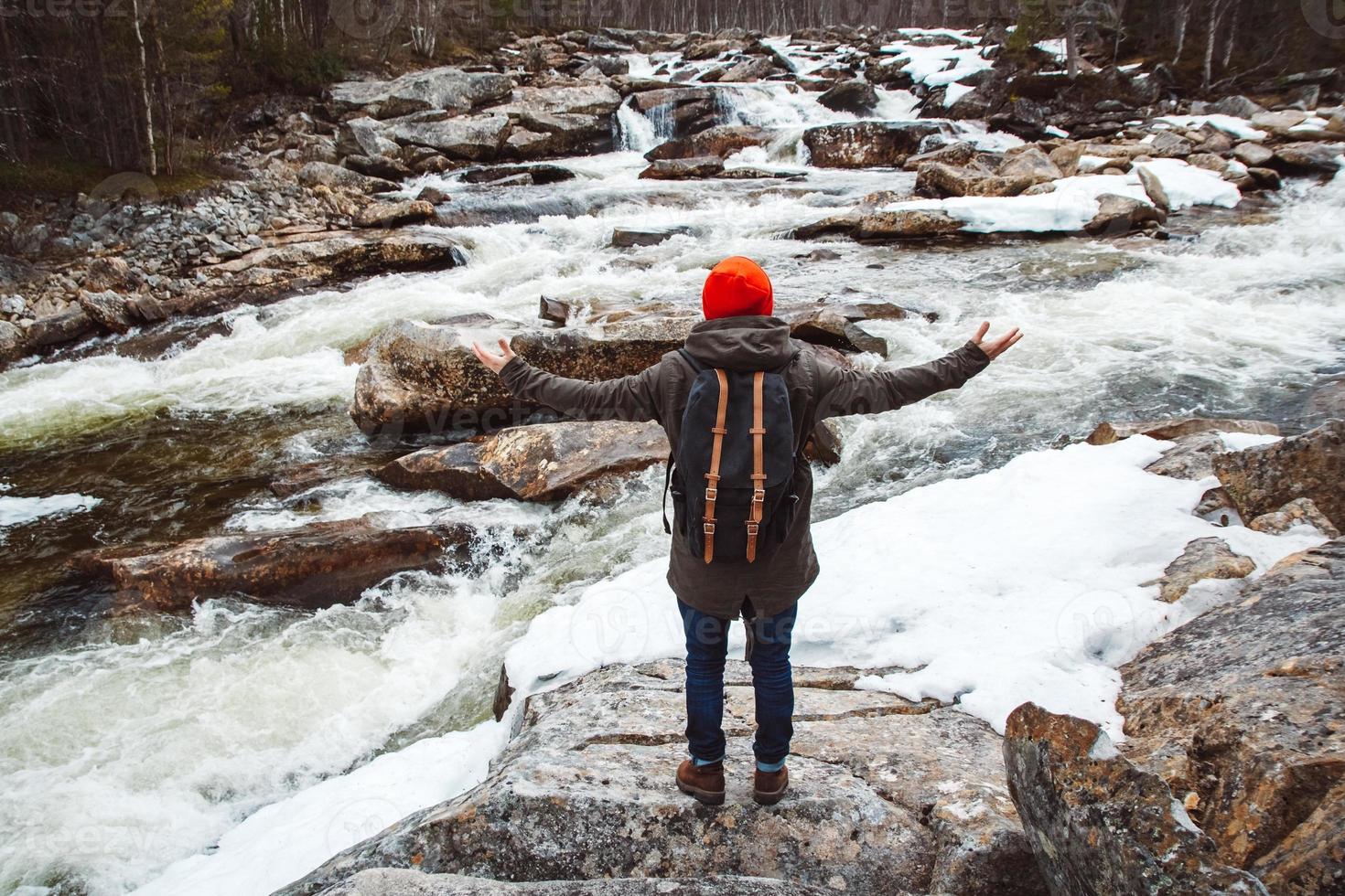 viaggiatore uomo in piedi su una roccia sul fiume di montagna e cascata foto