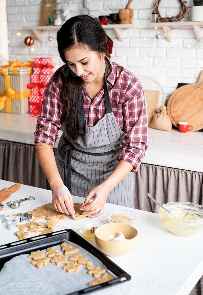 giovane donna bruna che cuoce i biscotti in cucina foto