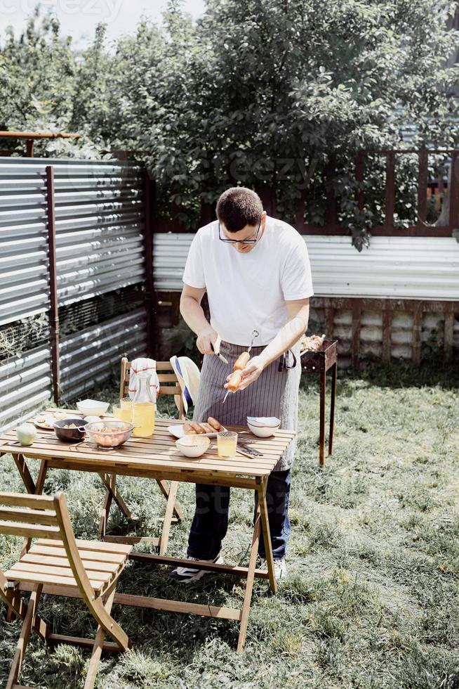 giovane grigliare spiedini su spiedini, uomo grigliare carne all'aperto foto