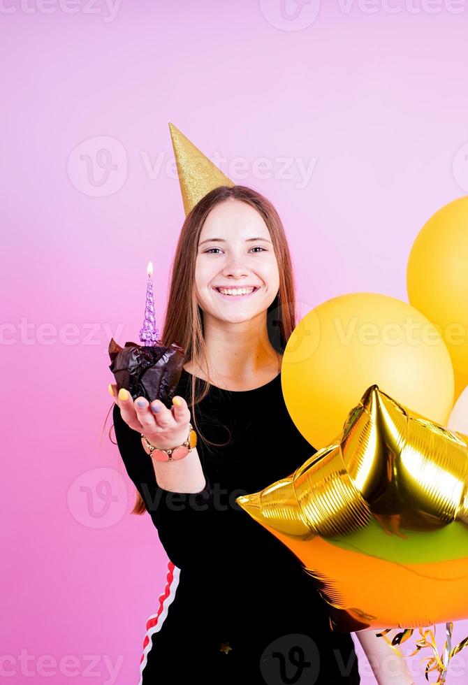 ragazza adolescente che tiene muffin con candele, esprimendo un desiderio foto