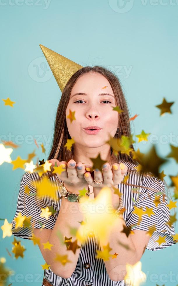 ragazza tennager che soffia coriandoli su sfondo blu foto