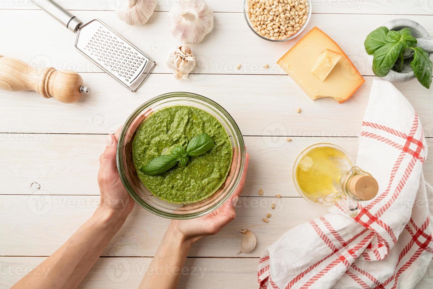 preparazione del pesto italiano. mani di donna che tengono una ciotola di pesto fatto in casa foto