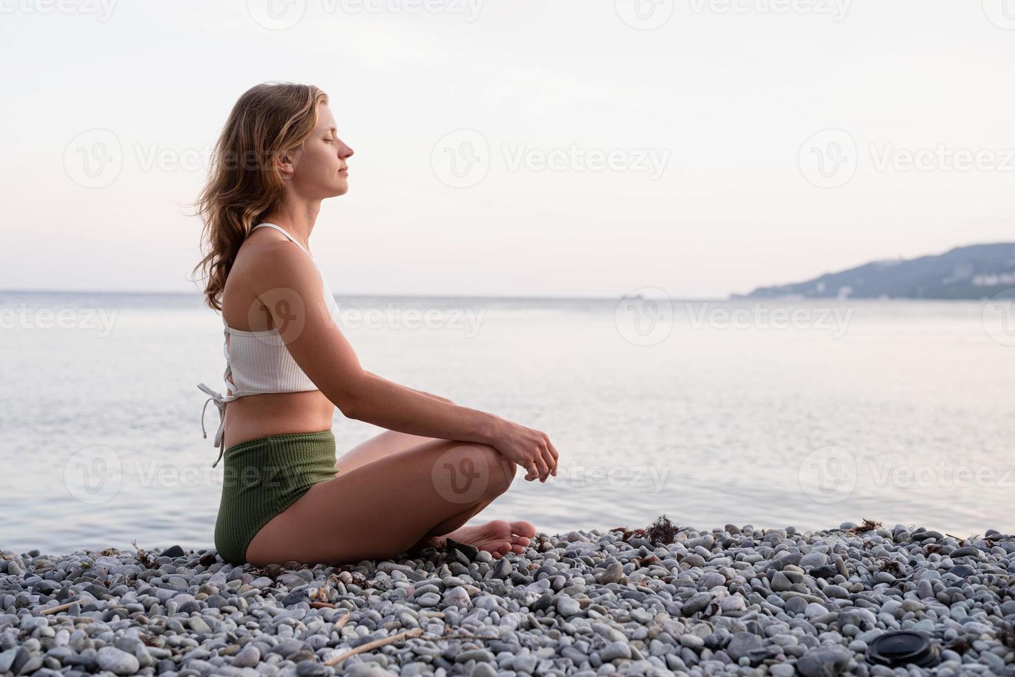 giovane donna che medita sulla spiaggia foto
