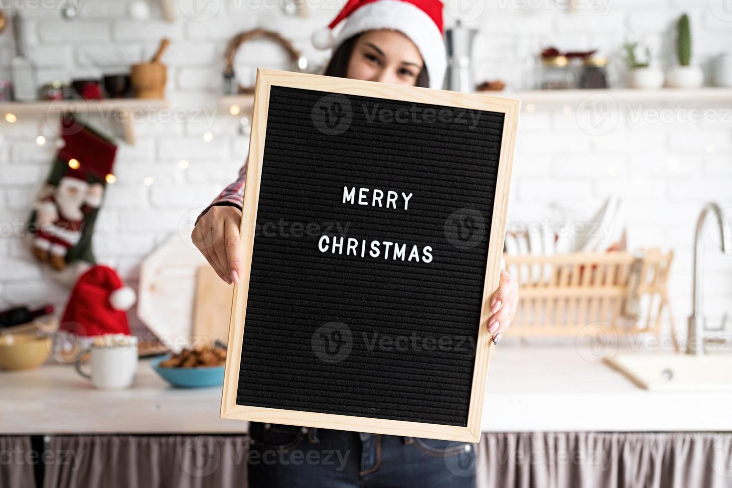 donna con cappello da babbo natale con cartellone nero foto