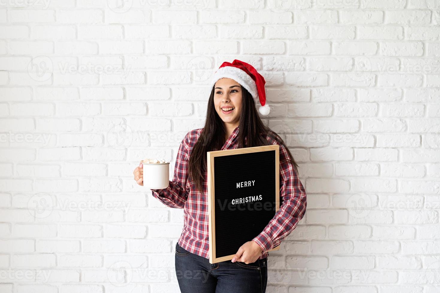 donna con cappello da babbo natale con cartellone nero foto