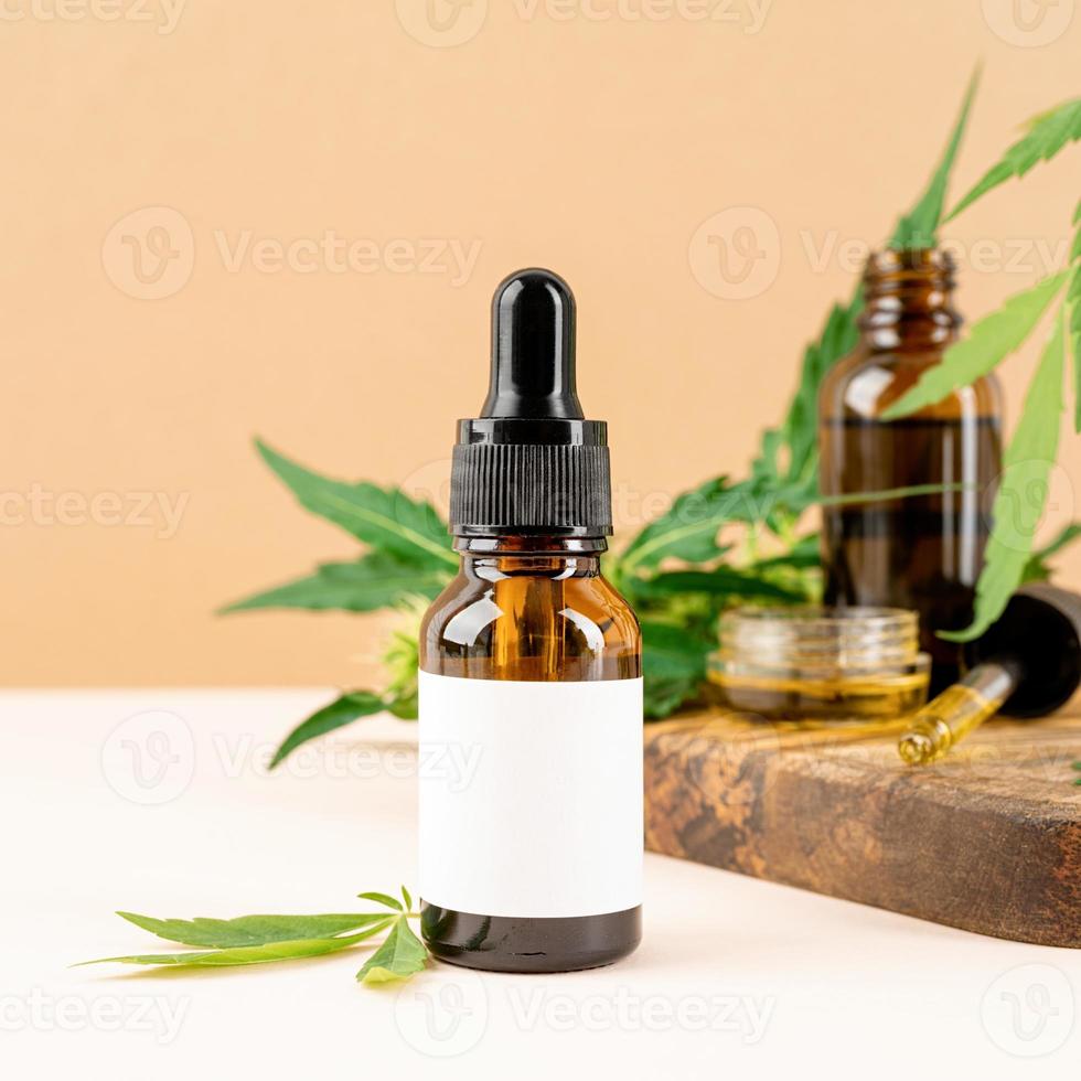 olio di CBD e foglie di cannabis cosmetici vista frontale su sfondo arancione foto