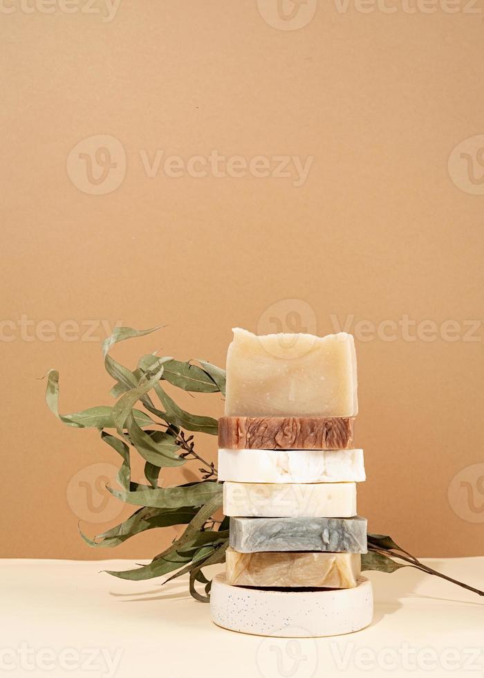 pila a torre di diversi saponi fatti a mano e foglie su sfondo crema foto