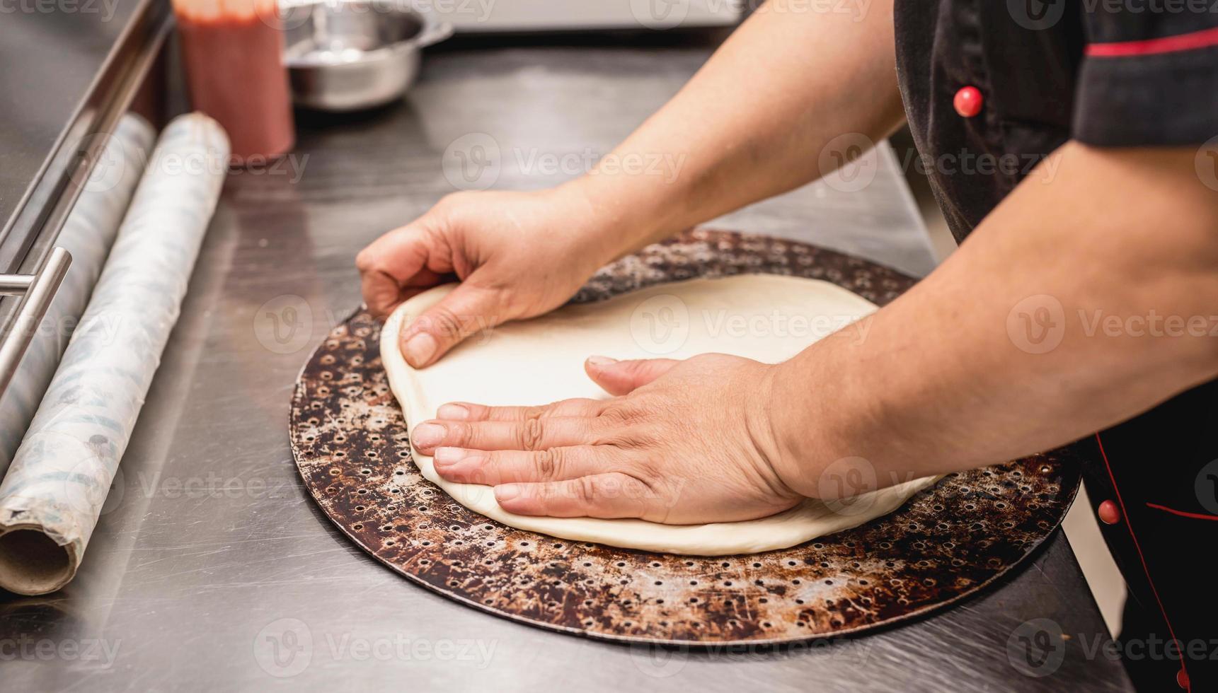 mani del fornaio che preparano l'impasto per la pizza foto