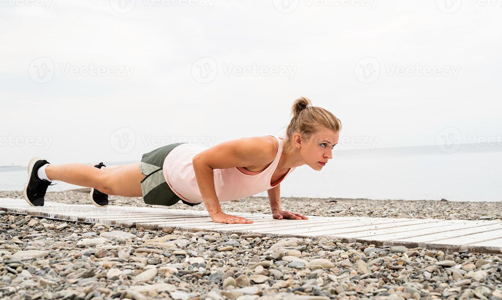 donna che fa le flessioni in riva al mare foto