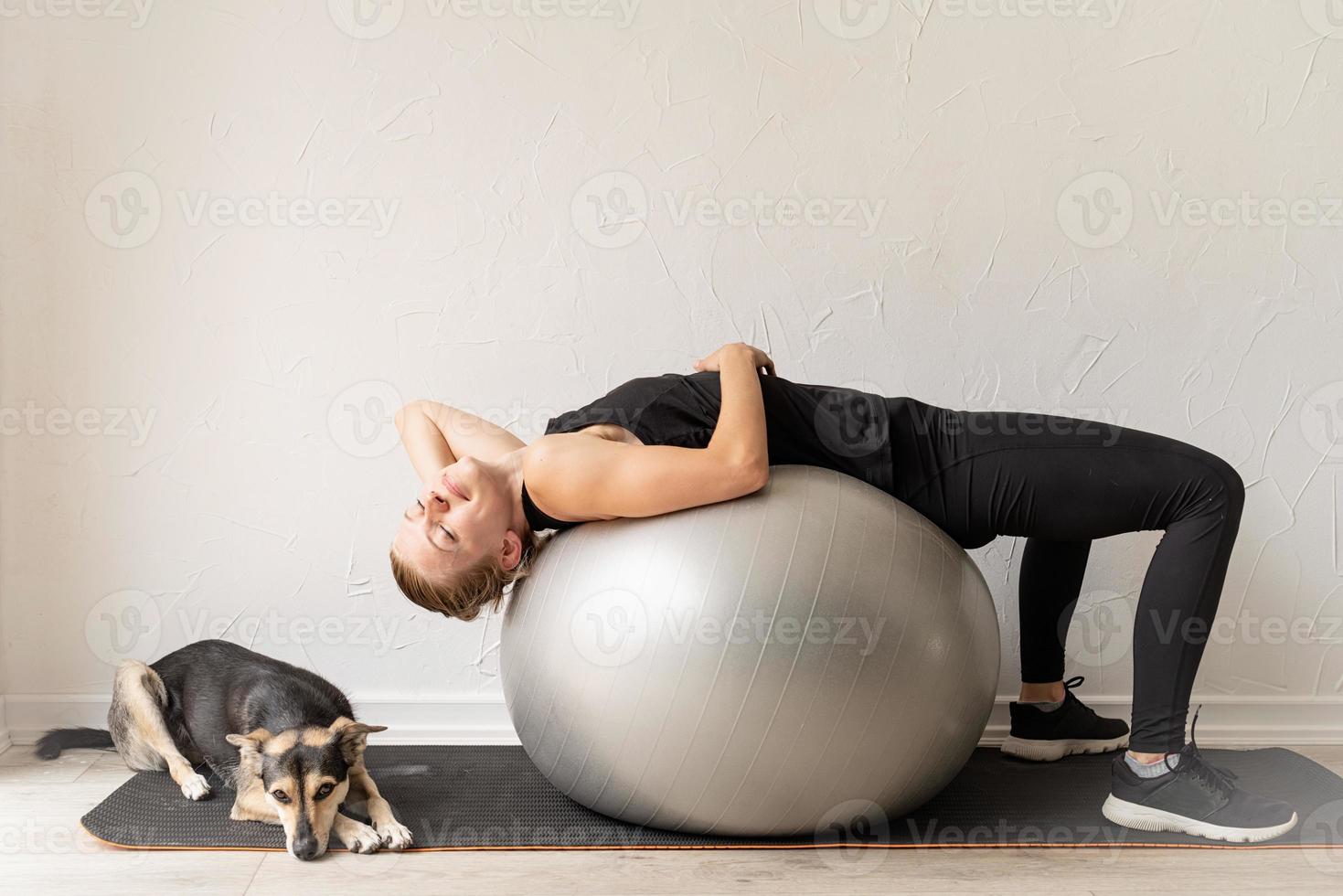 donna sdraiata sulla palla fitness in fase di riscaldamento prima dell'allenamento foto