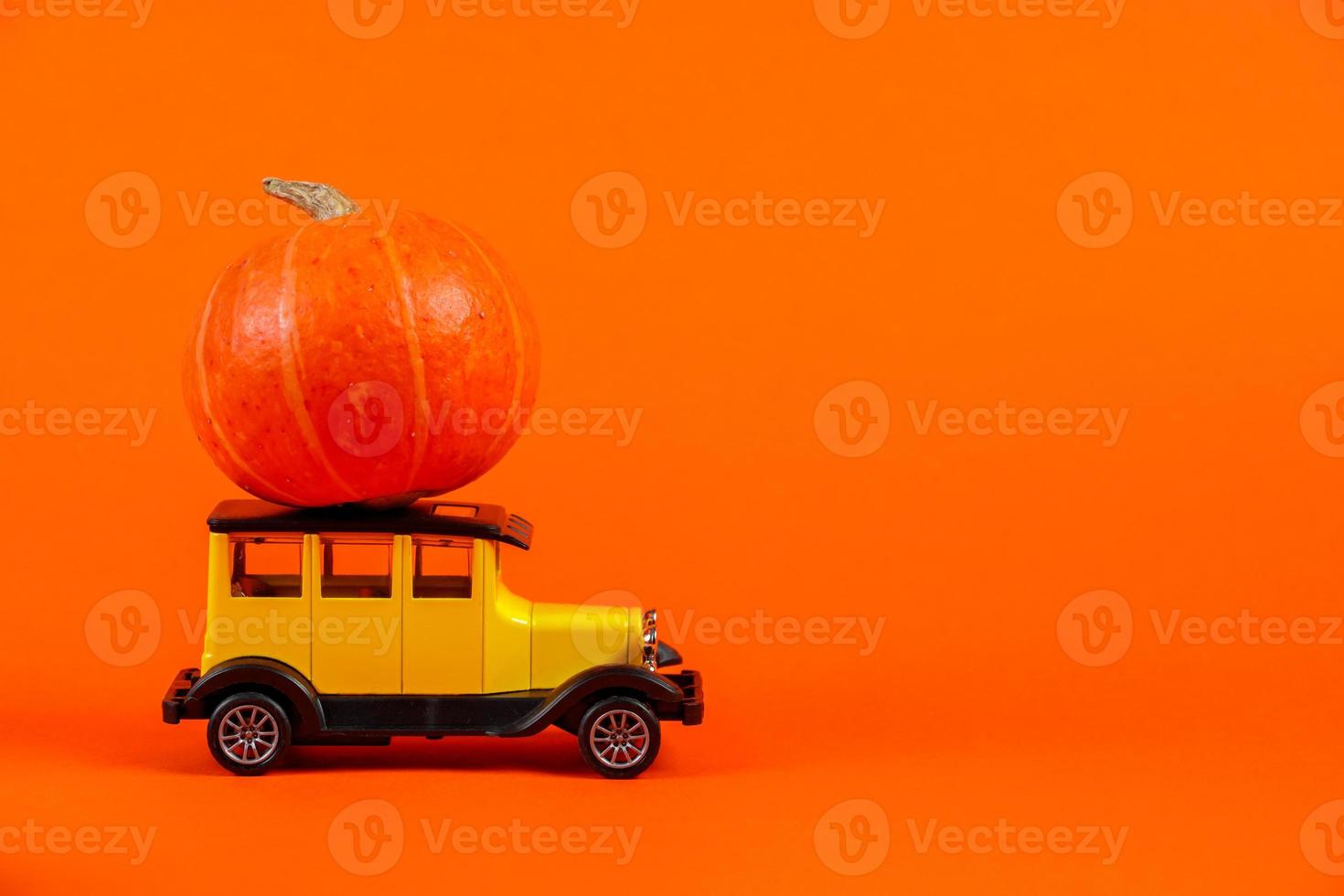 auto giocattolo retrò con una zucca su uno sfondo arancione. foto