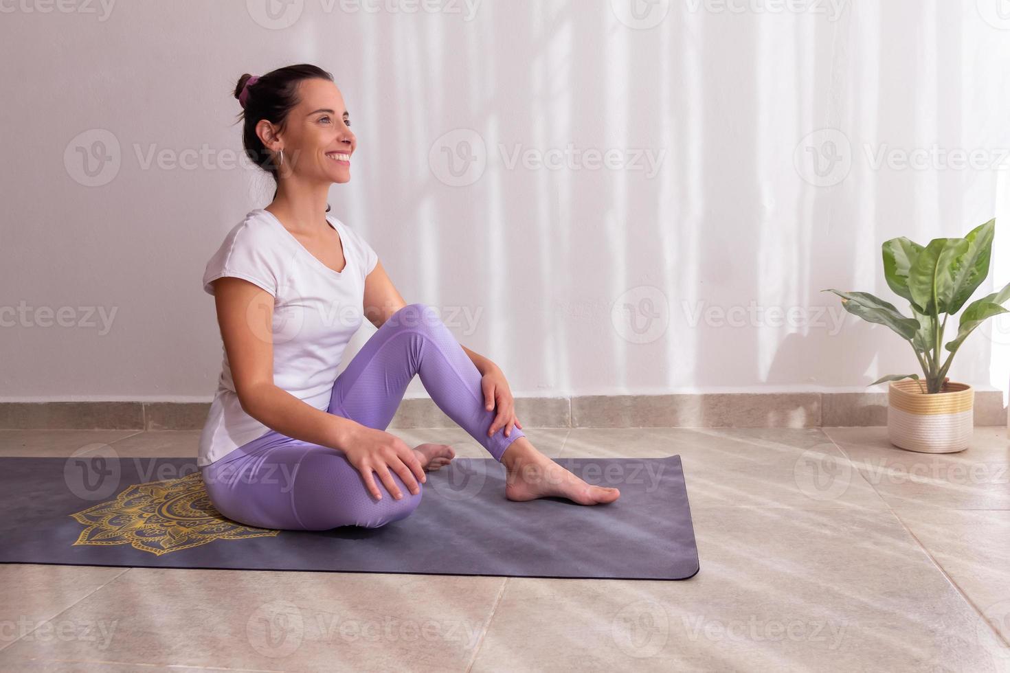 donna sorridente sul tappetino da yoga foto