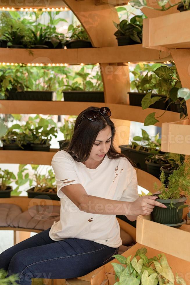 donna seduta sul divano nel centro commerciale, guardando le piante foto