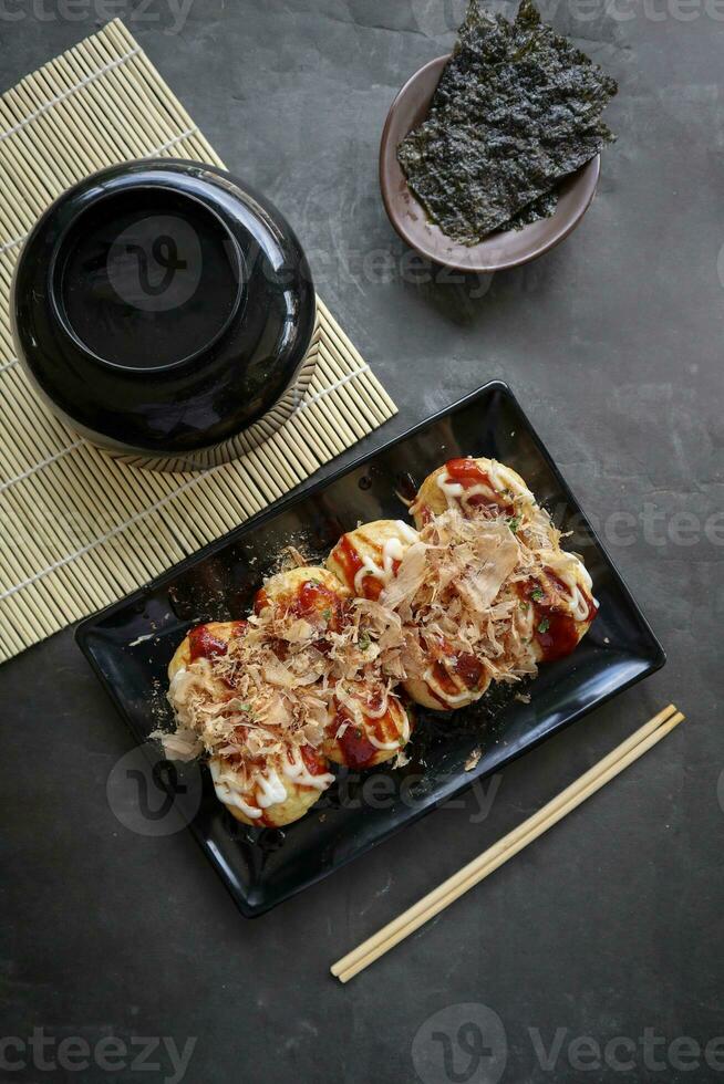 takoyaki è un' giapponese cibo, fatto a partire dal Grano Farina Impasto, polpo carne, o altro ripieni, servito con salsa, Maionese e guarnizione nel il modulo di katsuobushi o legna pesce trucioli. foto