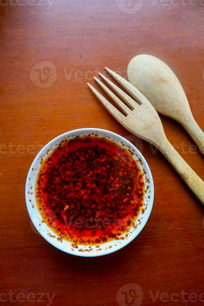 peperoncino olio. fatti in casa peperoncino olio nel un' bicchiere liite piatto, su tavolo foto