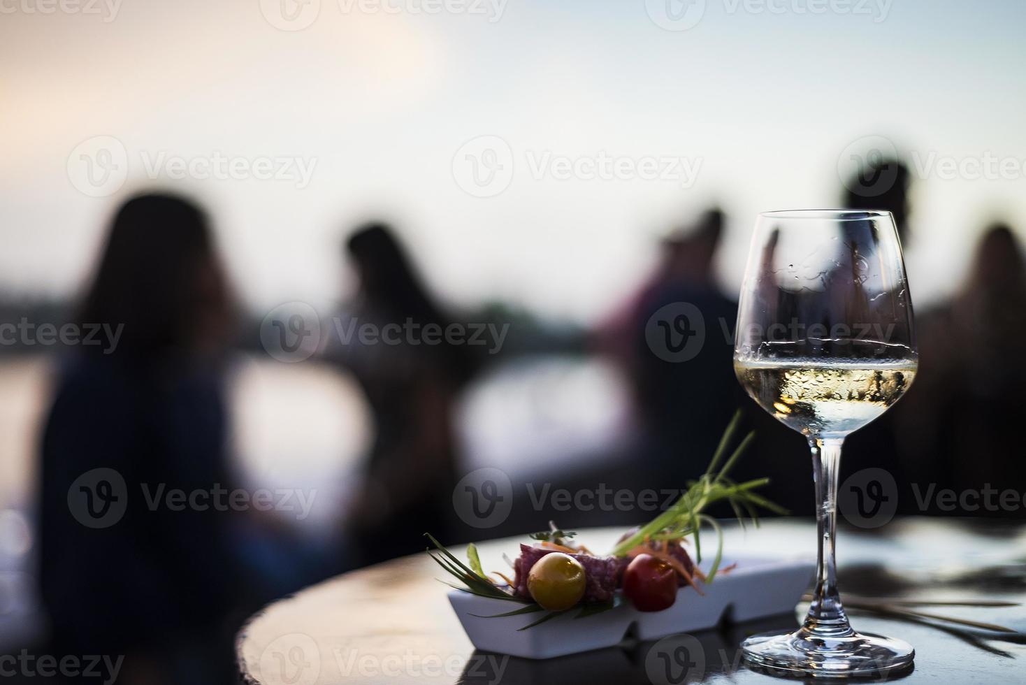 bicchiere di vino bianco con cibo gourmet tapas snack nel bar all'aperto al tramonto foto