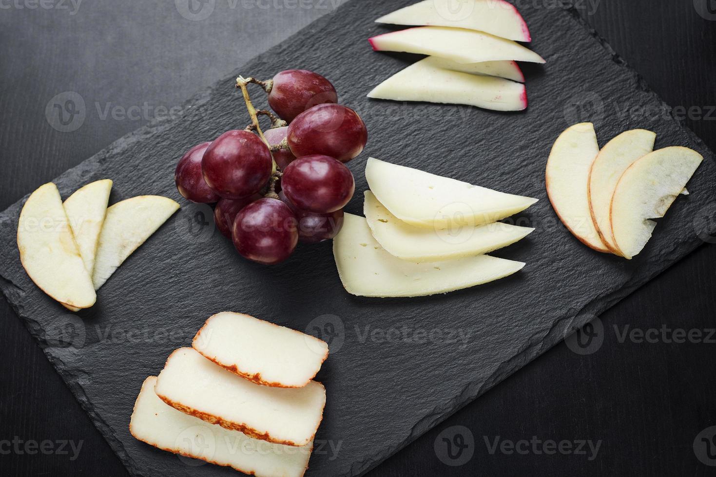 antipasto di tapas gourmet di tagliere di formaggi misti con merenda di mele e uva foto
