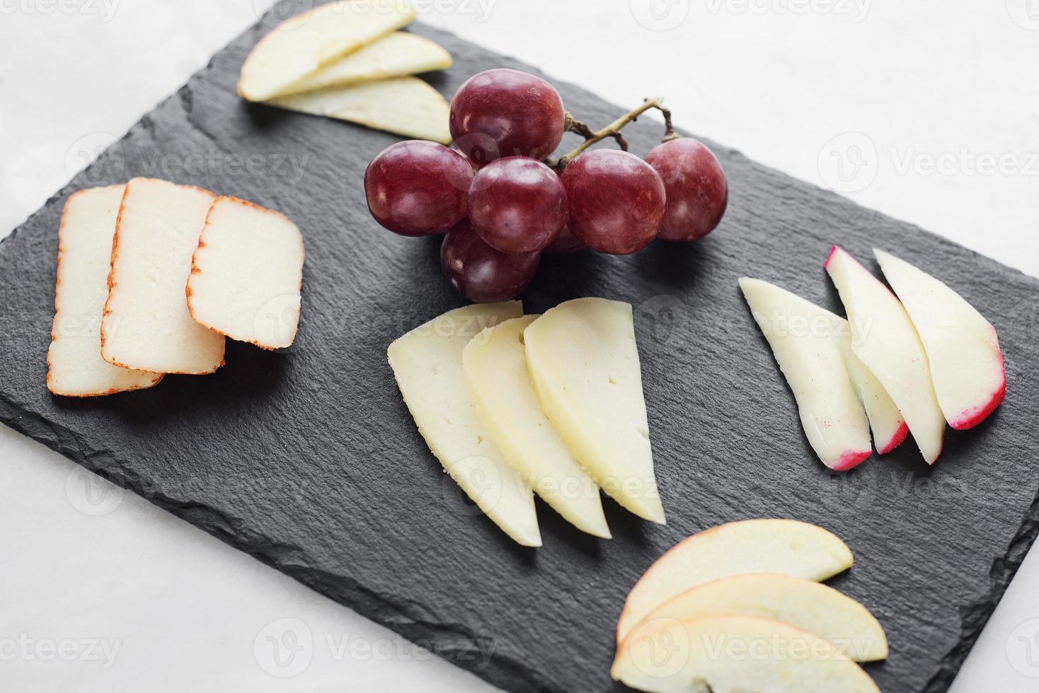 antipasto di tapas gourmet di tagliere di formaggi misti con merenda di mele e uva foto