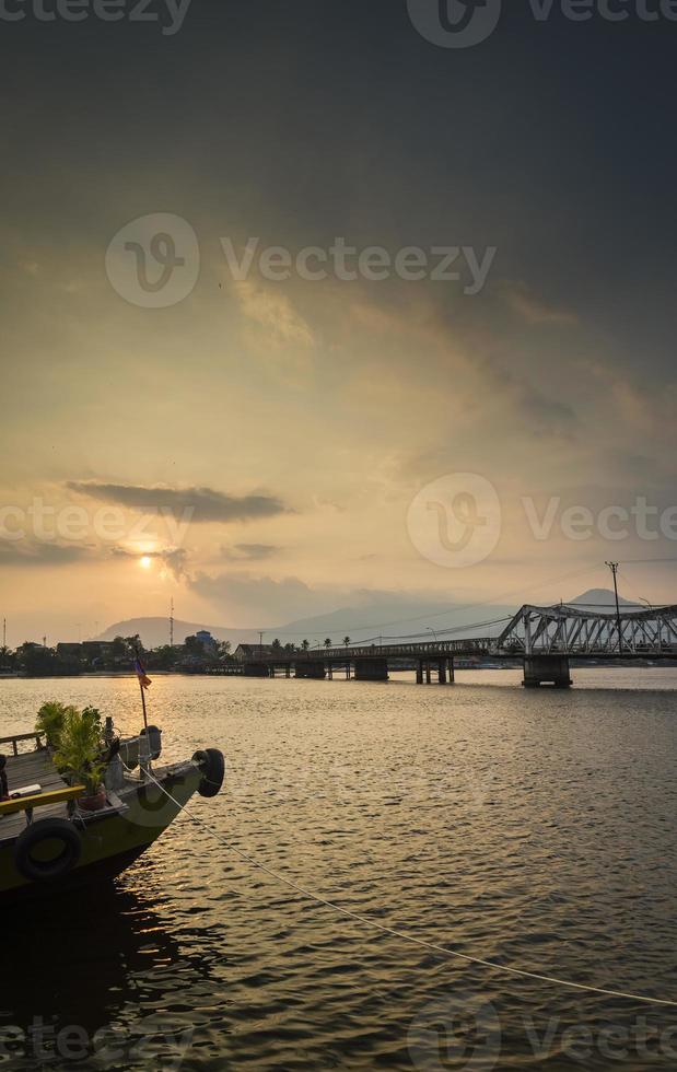 punto di riferimento vecchio ponte e fiume al tramonto in kampot cambogia foto