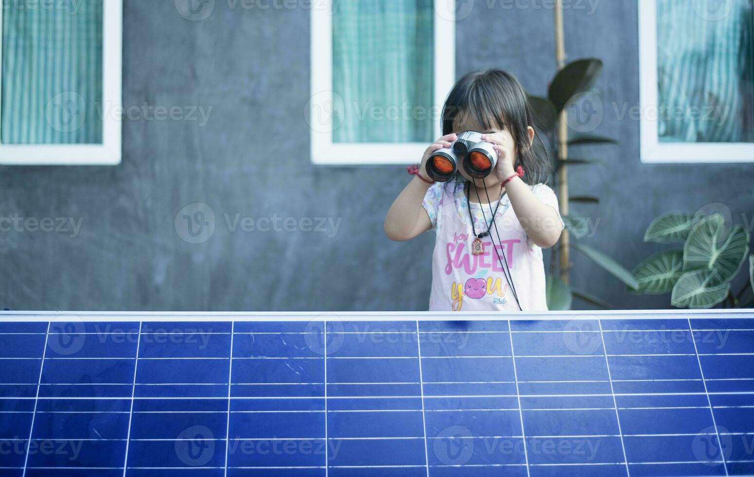 contento asiatico ragazza ammirazione solare pannelli con binocolo recentemente installato a casa. foto