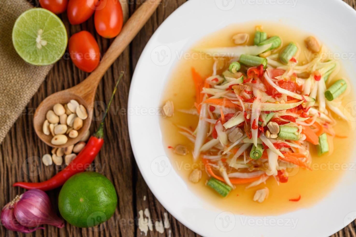 insalata di papaya su un piatto bianco su un tavolo di legno foto