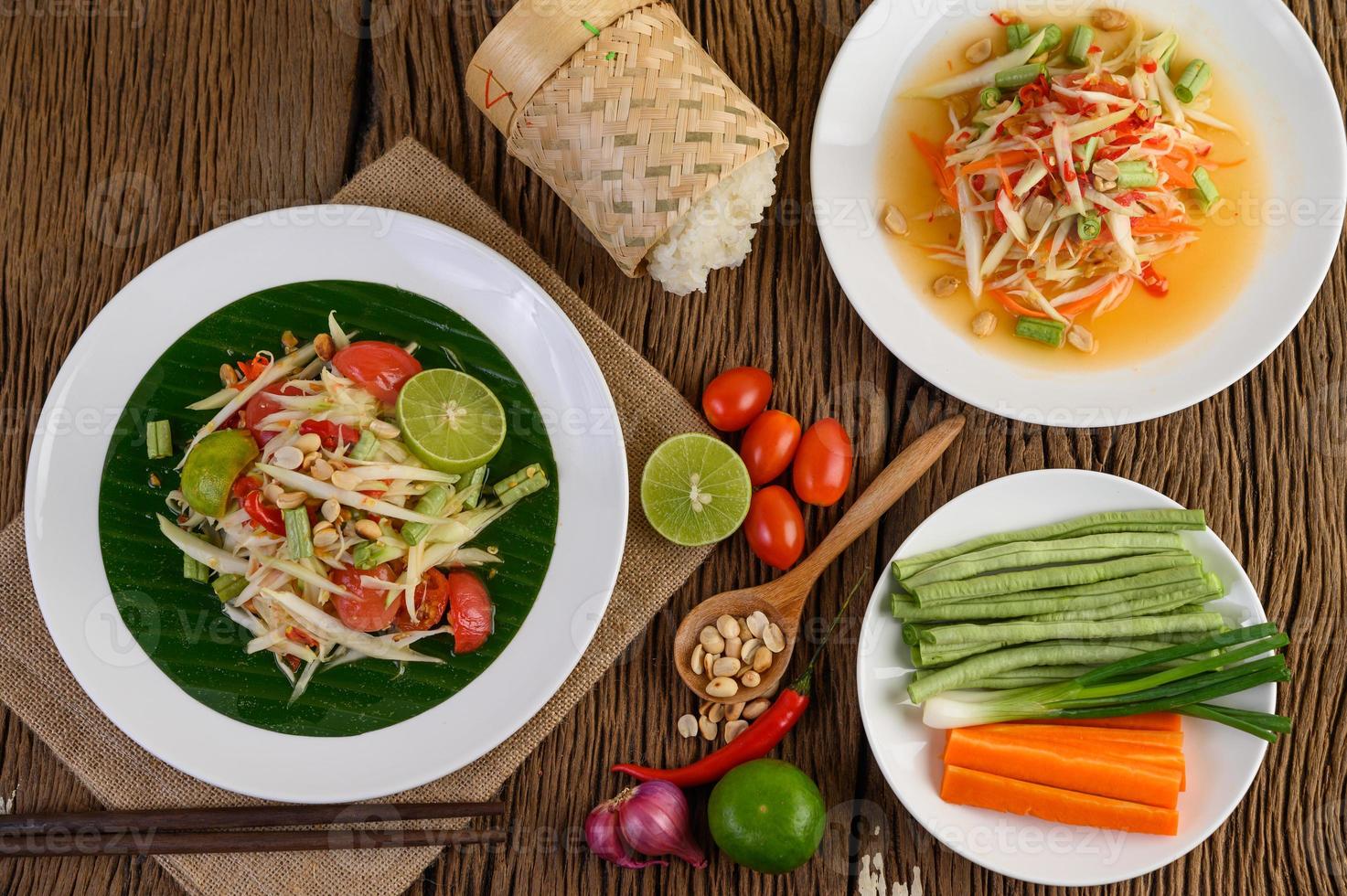 insalata di papaya su un piatto bianco su un tavolo di legno foto