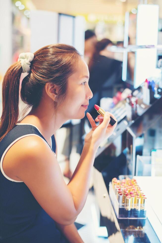 bella giovane donna seleziona il rossetto di colore per l'acquisto allo shopping foto