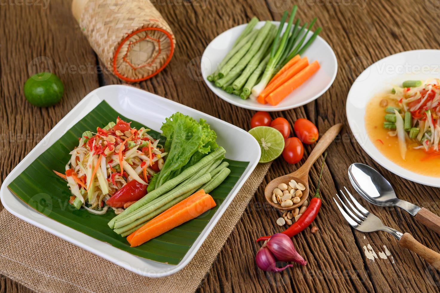 insalata di papaya su un piatto bianco su un tavolo di legno foto