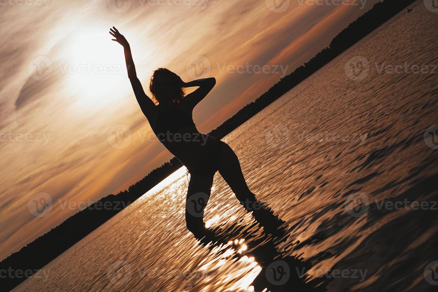 donna spensierata felice che gode del bel tramonto sulla spiaggia foto