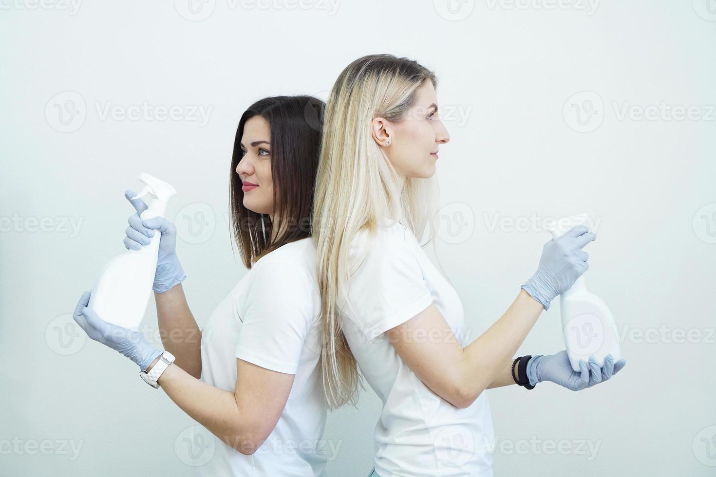 due donne tengono il flacone spray - antisettico o detergente come pistole foto