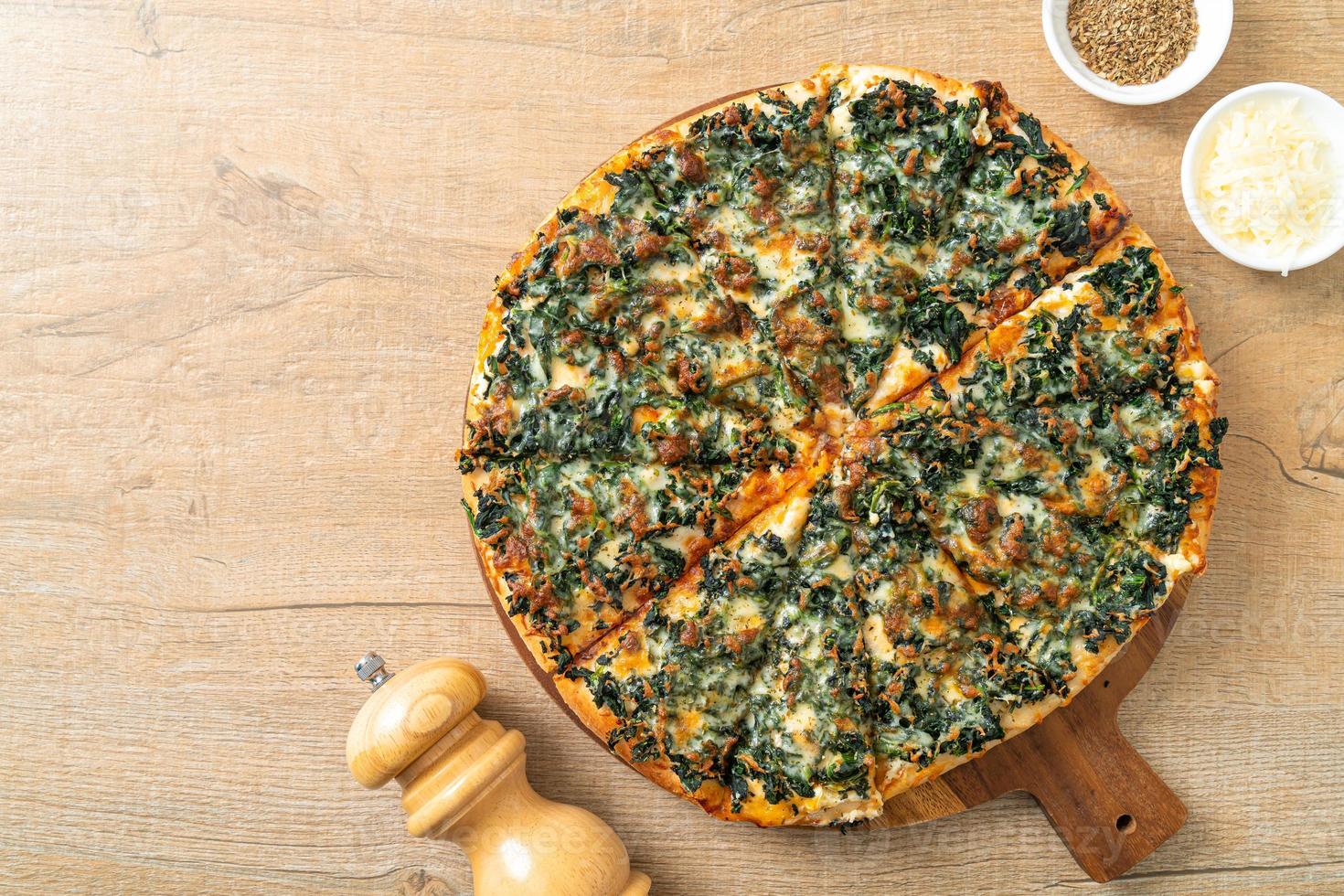 pizza spinaci e formaggio su teglia di legno foto