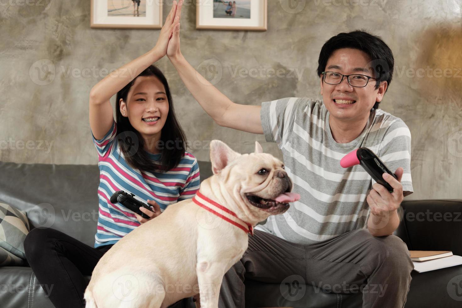 la coppia asiatica sta giocando ai videogiochi e al cane da compagnia nelle vicinanze. foto