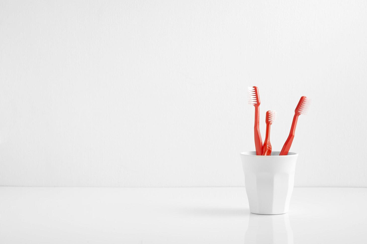 gruppo di spazzolino da denti rosso in un bicchiere di plastica, spazzolino da denti in bagno foto