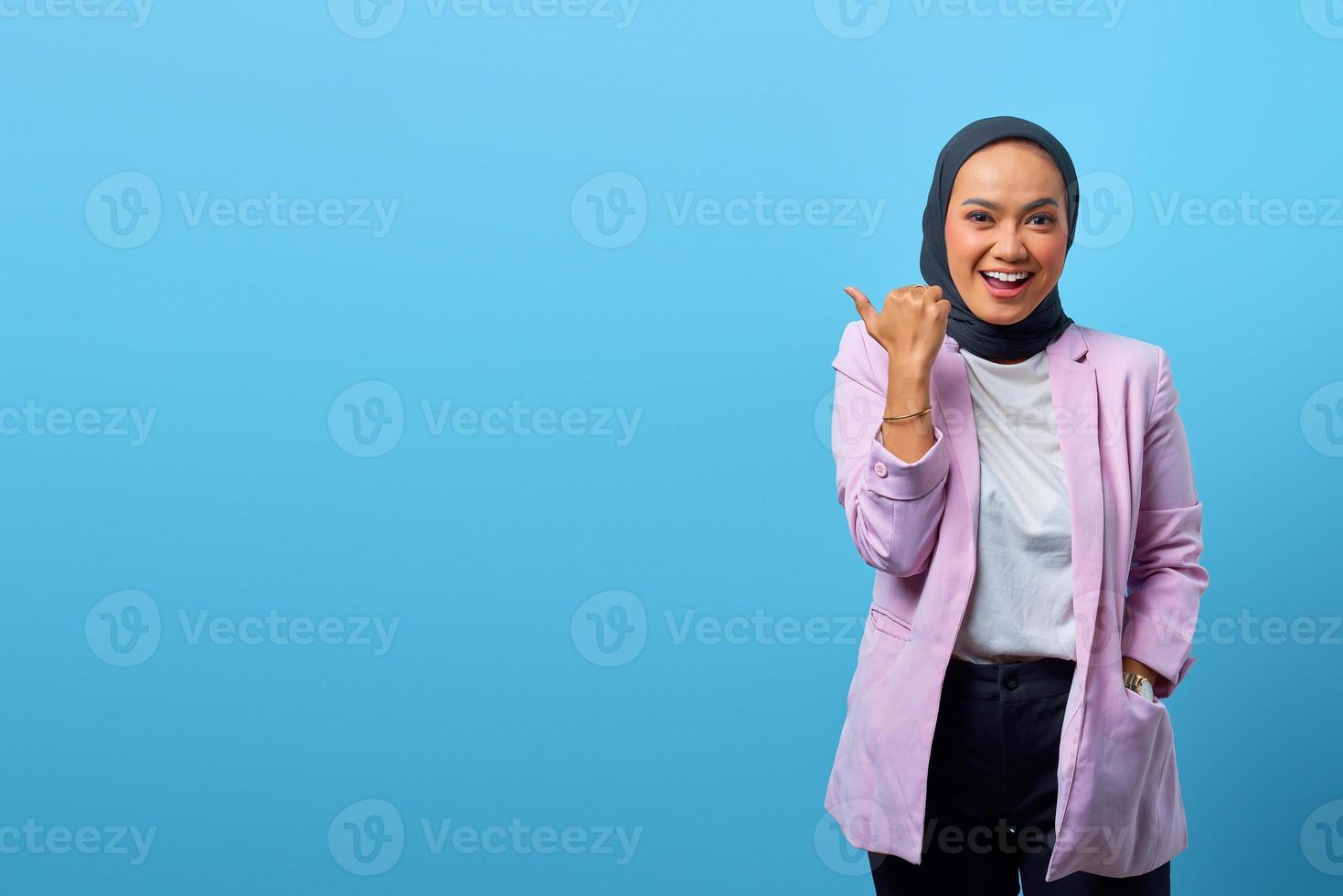 allegra donna asiatica che punta il dito verso lo spazio vuoto foto