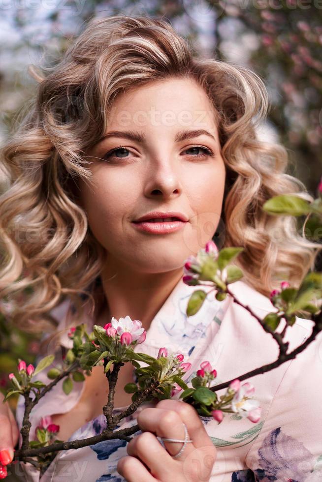 romantica giovane donna nel giardino primaverile tra i fiori di melo. foto