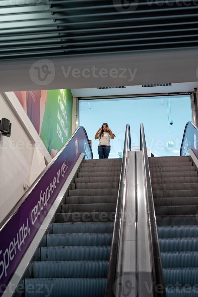 giovane donna in piedi sulla scala mobile nel centro commerciale shopping foto
