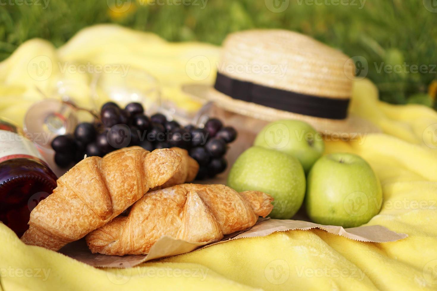 picnic sull'erba con croissant, vino rosato, cappello di paglia, uva foto