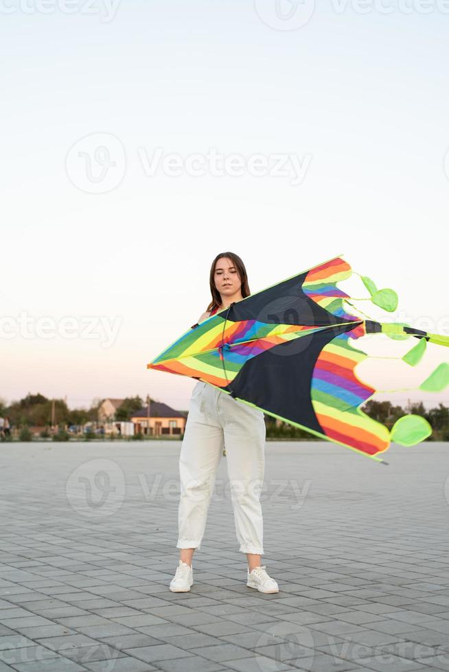 giovane donna che fa volare un aquilone in un parco pubblico al tramonto foto